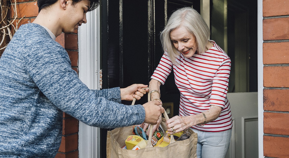 Ein Jugendlicher hilft einer älteren Dame beim Erledigen der Einkäufe